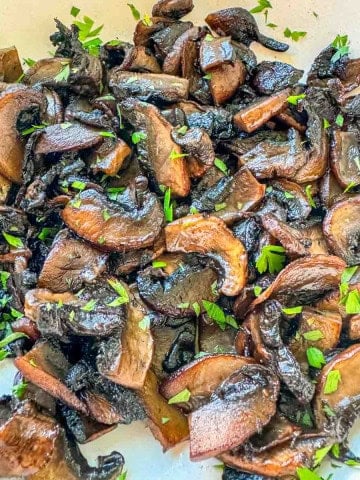 Golden sautéed mushrooms with fresh parsley garnish.