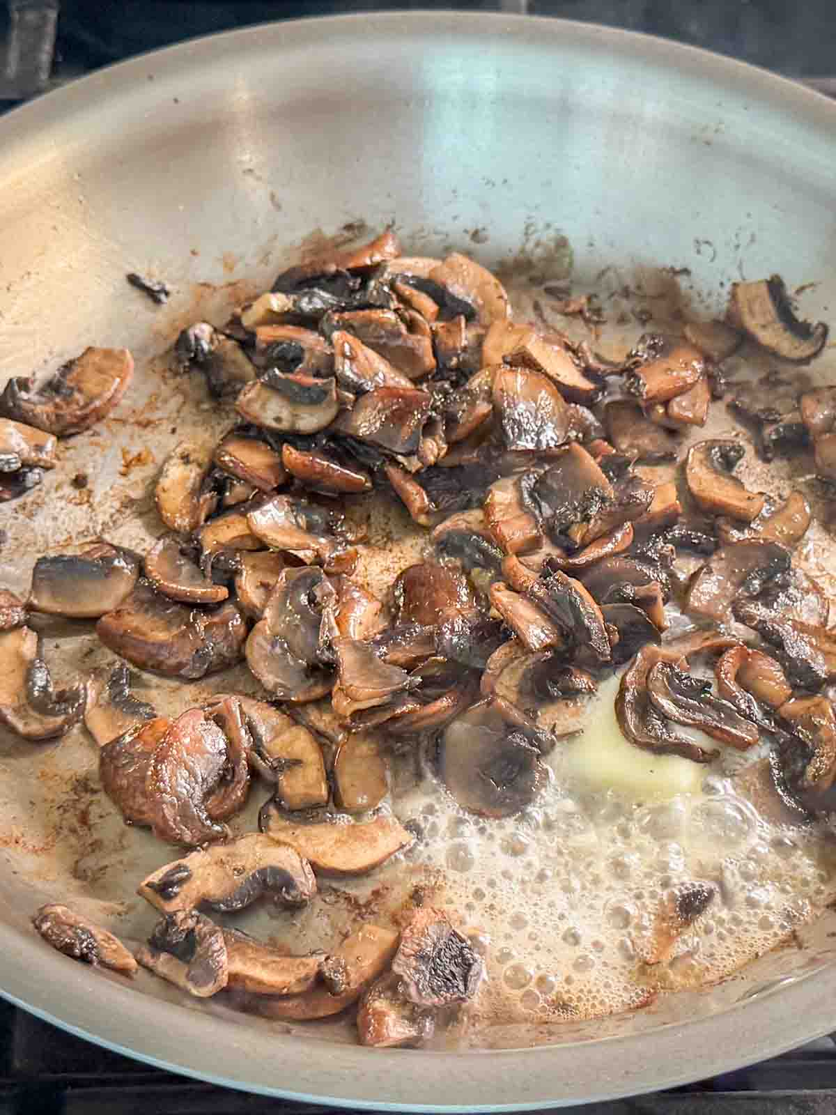 Golden saut&eacute;ed mushrooms in a skillet.