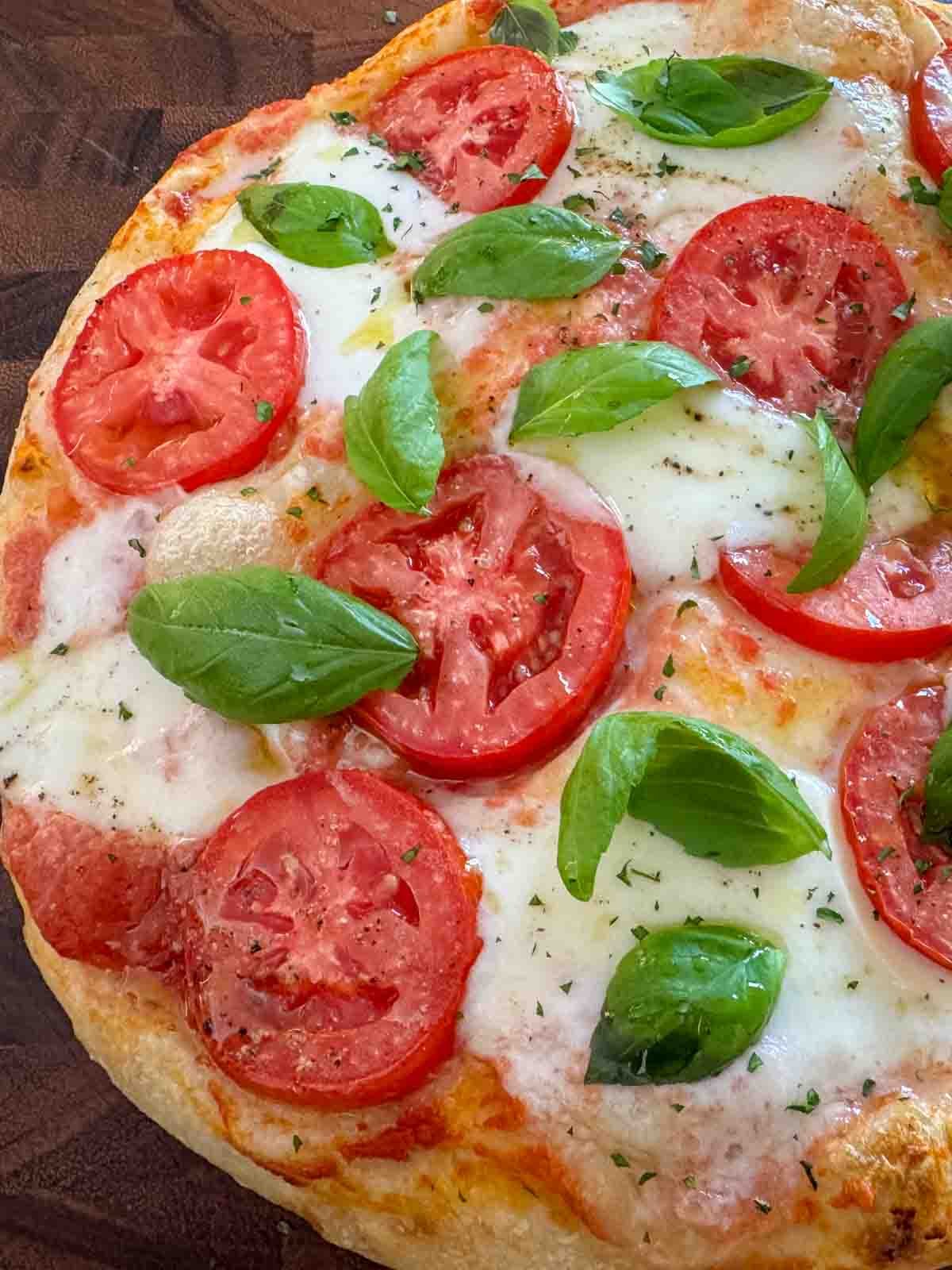 Freshly baked Margherita pizza on a wooden board, topped with melted mozzarella and fresh basil.