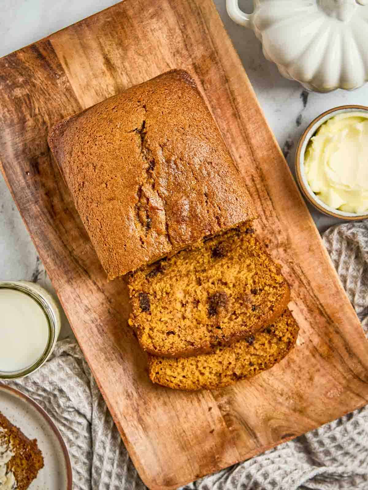 Old-fashioned pumpkin bread loaf sliced on a wooden board, showing moist texture and golden brown crust.