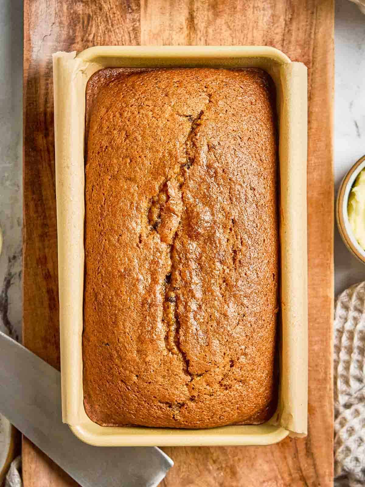 Whole loaf of homemade pumpkin bread in pan with parchment paper.