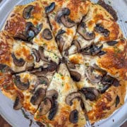 Sliced Homemade white pizza with mozzarella, sautéed mushrooms, and garlic oil.