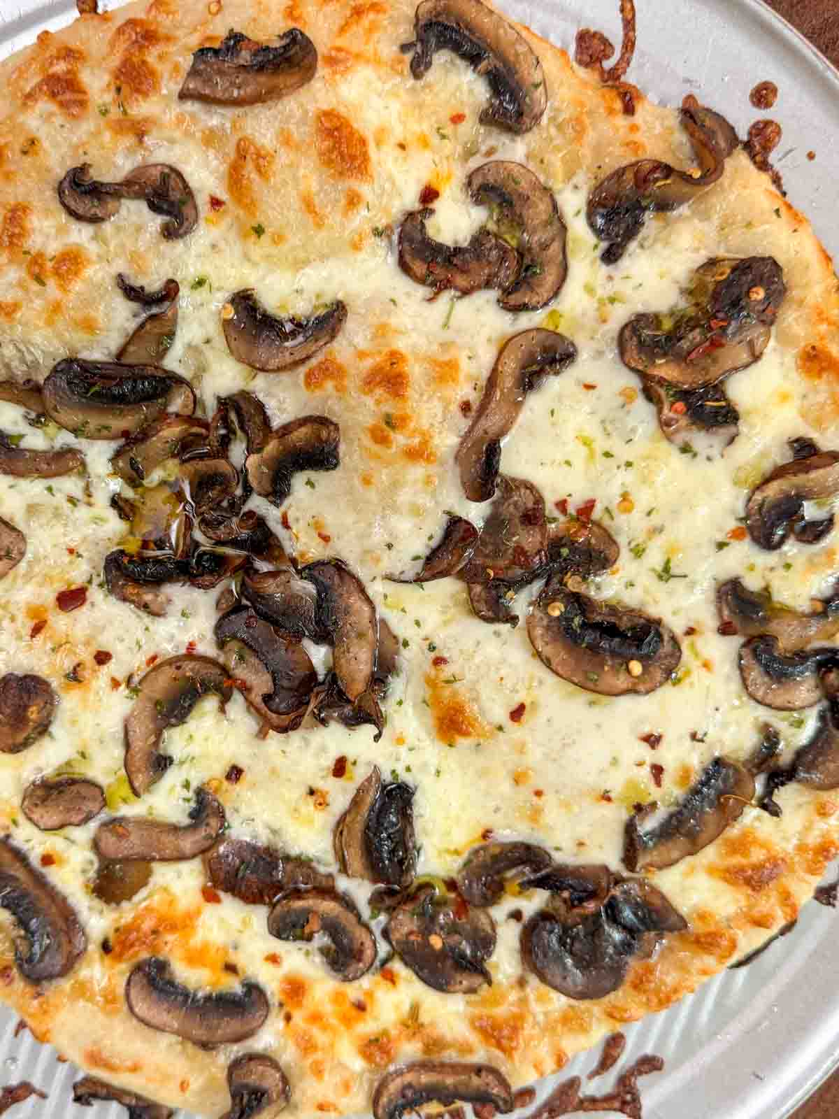 Homemade white pizza with mozzarella, sautéed mushrooms, and garlic oil.
