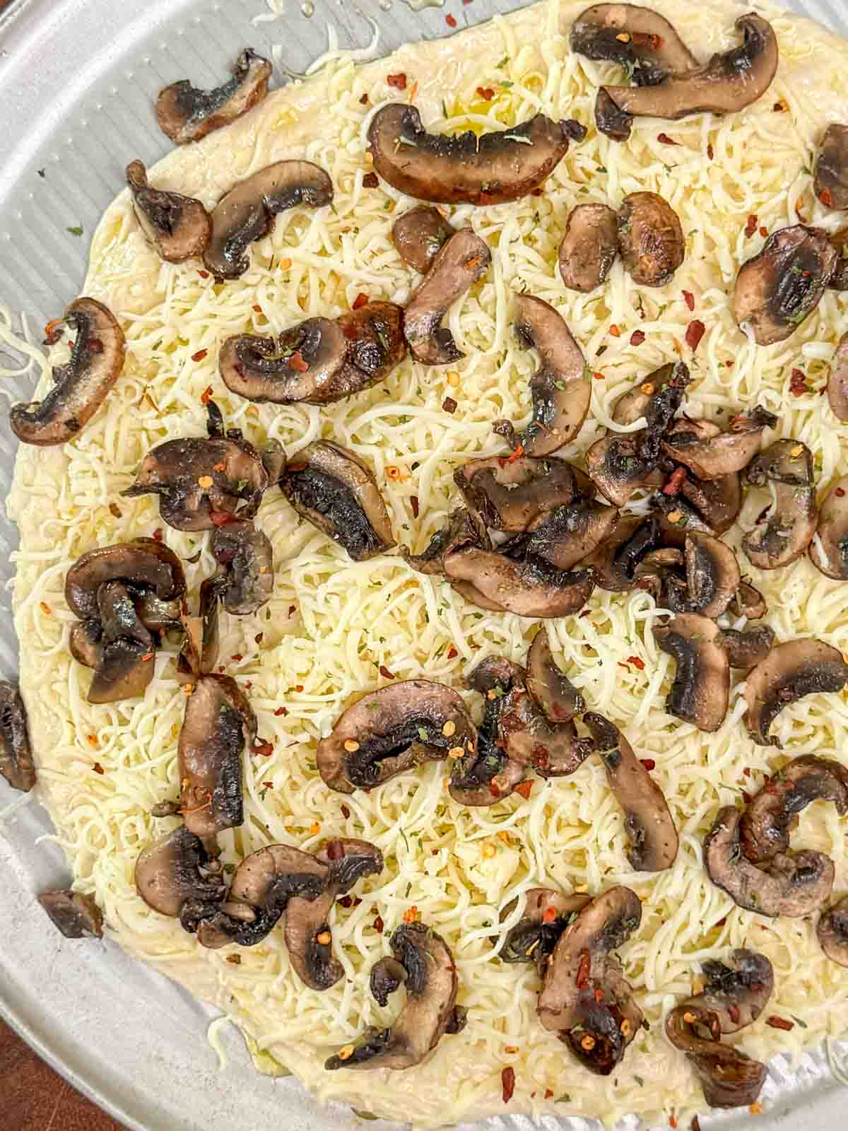 Homemade white pizza with mozzarella, sautéed mushrooms, and garlic oil ready to be baked.