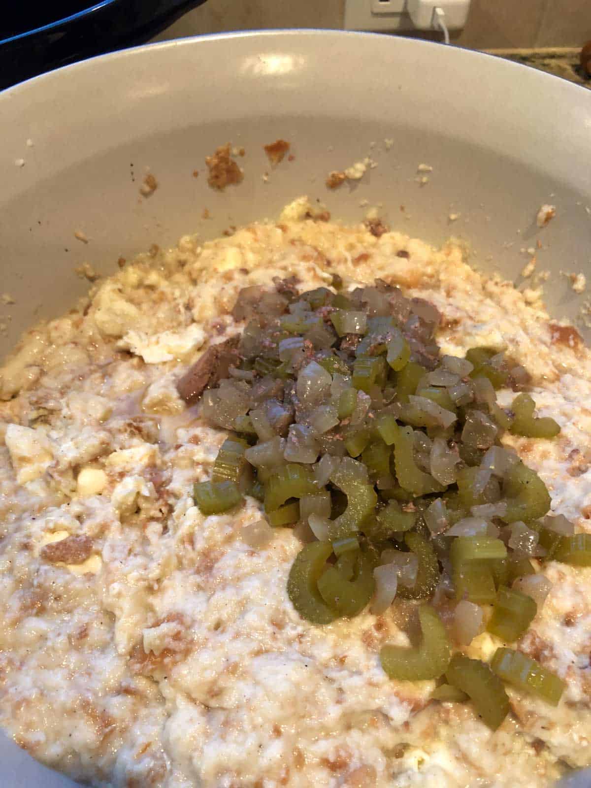 Celery and onions added to the bowl of torn bread with melted butter and warm broth.