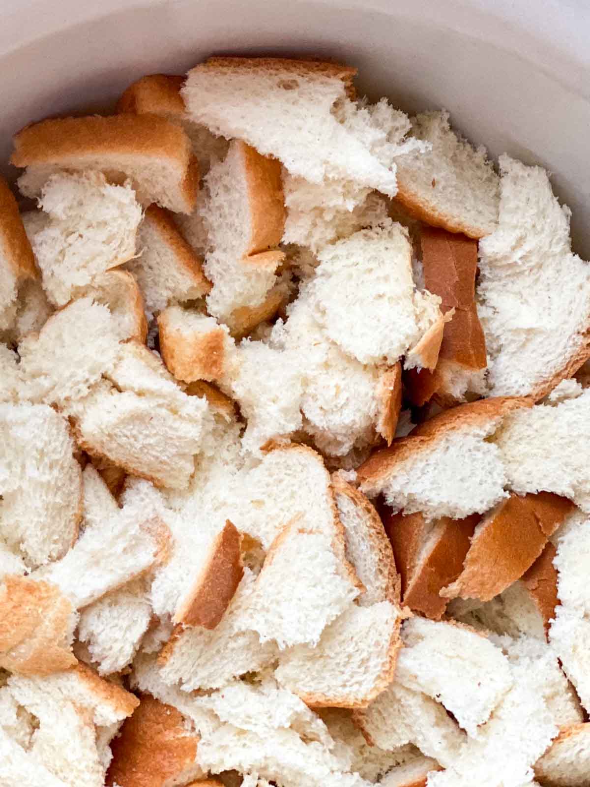 Torn white sandwich bread in a large mixing bowl for stuffing.