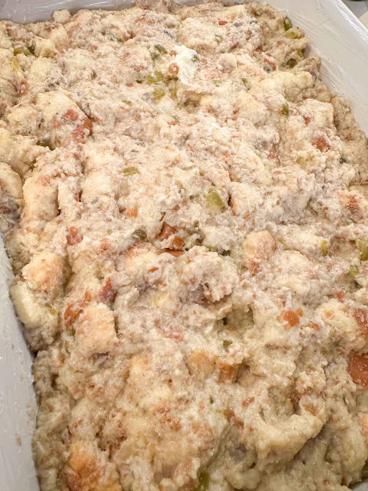 Stuffing in a white casserole dish ready to bake in the oven.