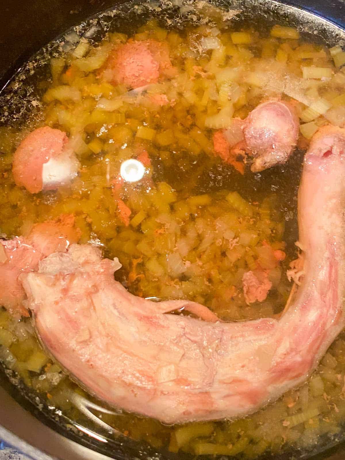Turkey neck and giblets simmering with celery and onion in a pot to make homemade broth.