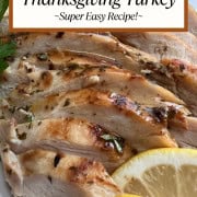 Sliced Thanksgiving turkey arranged on a platter with fresh herbs and lemon slices.