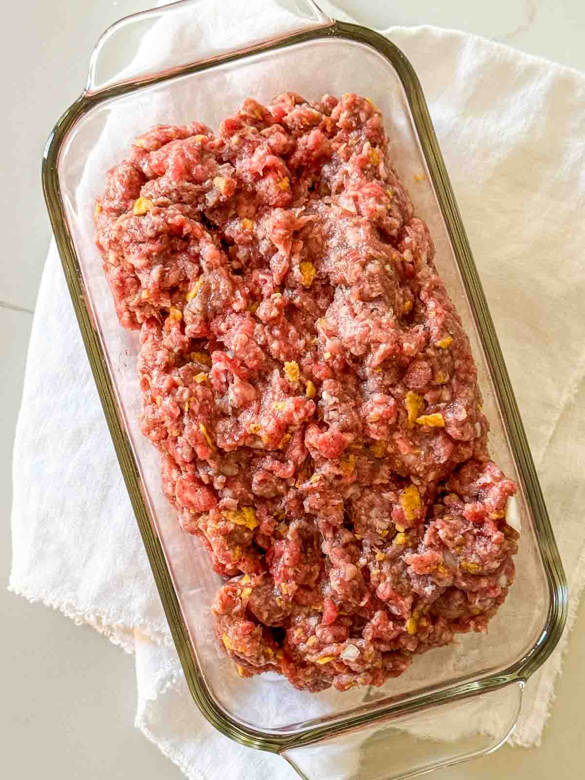 Classic Midwestern meatloaf with ketchup topping sliced in a loaf pan ready to be baked in the oven.
