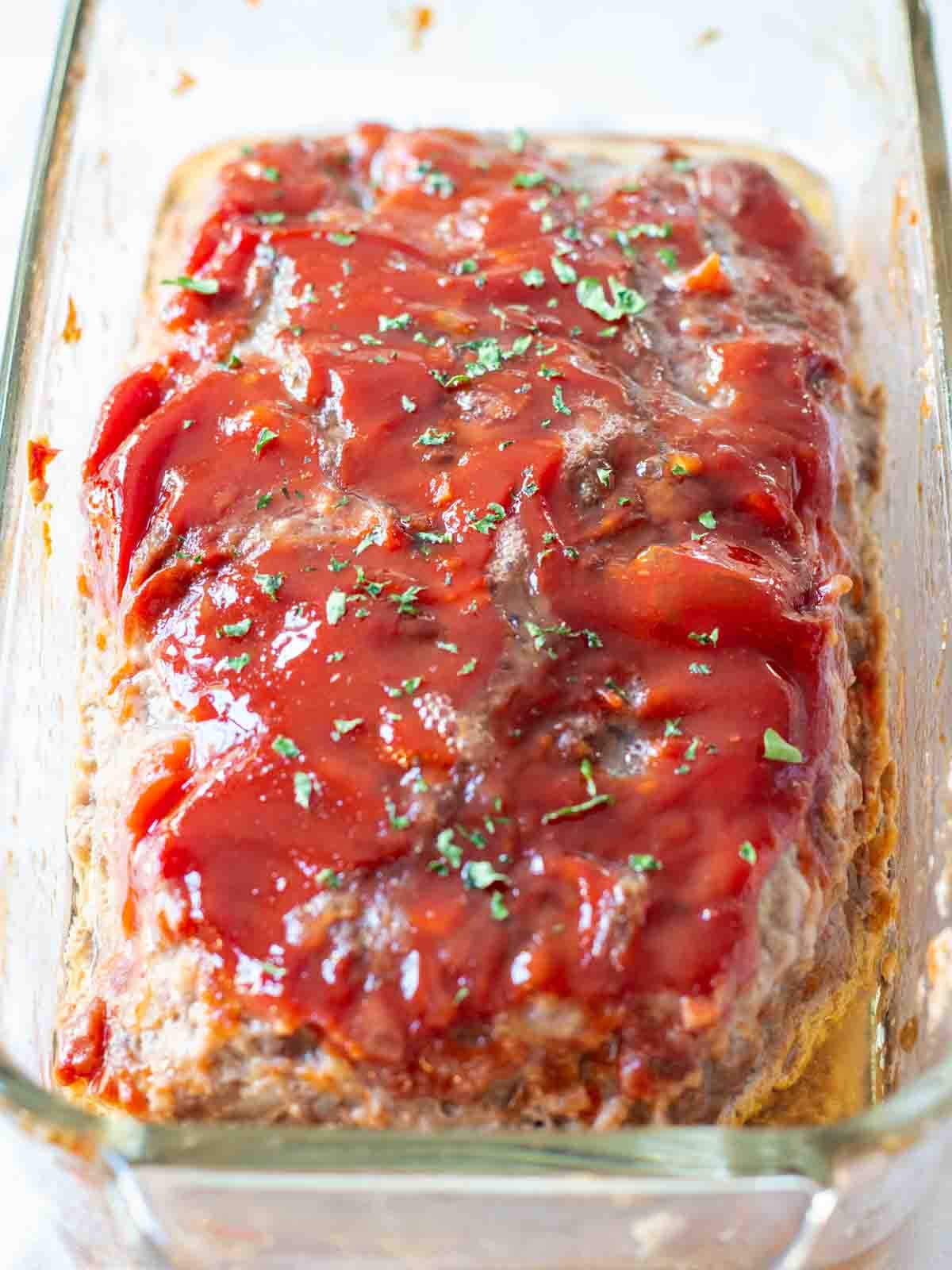 Classic Midwestern meatloaf with ketchup topping sliced in a loaf pan.