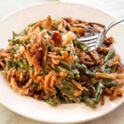 A serving of green bean casserole topped with French’s crispy fried onions on a white plate.