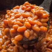 Close-up of homemade baked beans with a rich, glossy sauce, served in a black pot, highlighting the hearty texture and vibrant color.