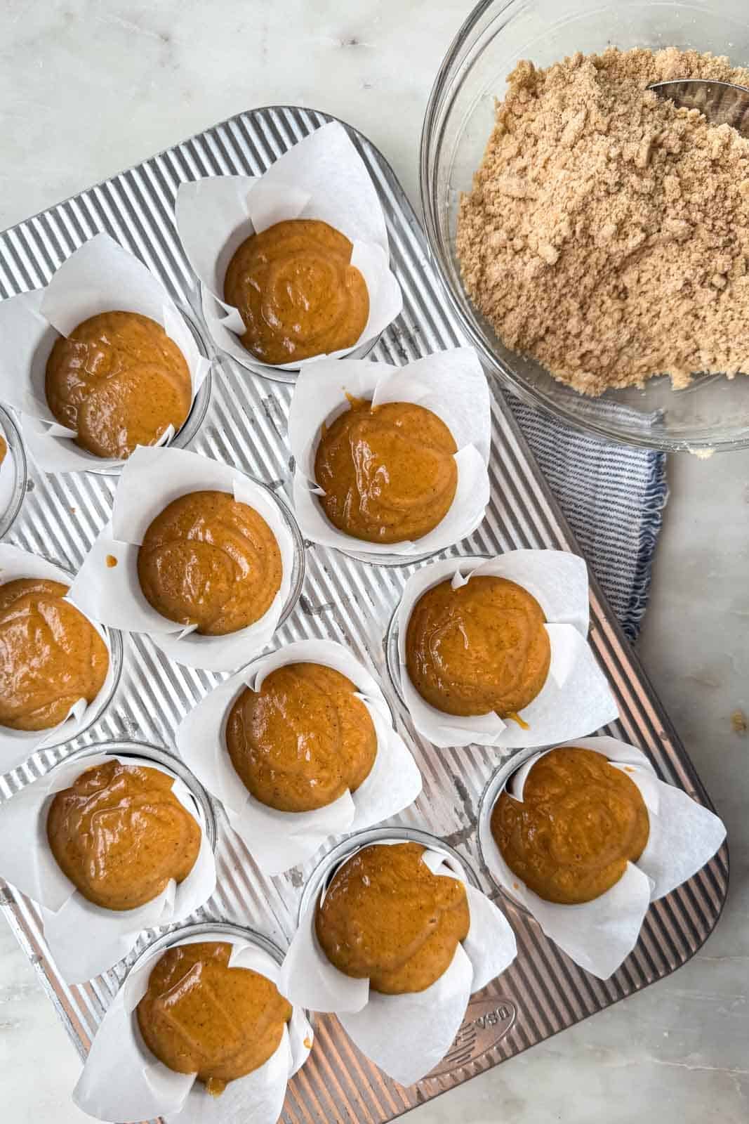 Pumpkin muffin batter divided among 12 muffin cups and filled about three-quarters full.