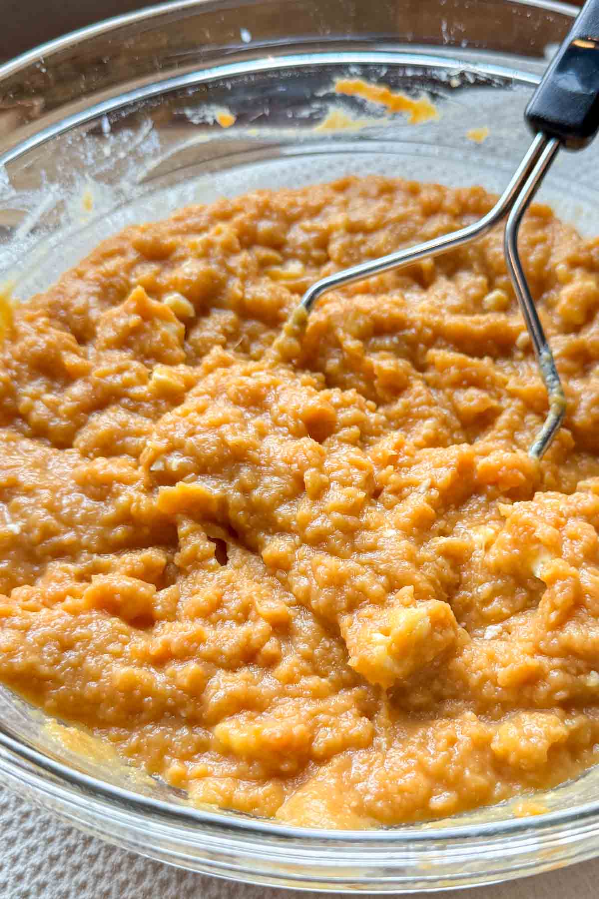 Creamy sweet potato casserole filling mixed in a glass bowl.