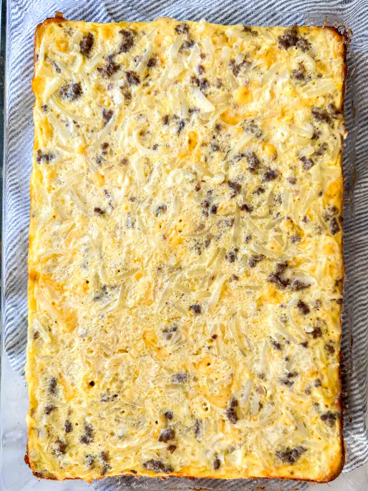 Baked sausage hash brown breakfast casserole with melted cheese and lightly golden edges.
