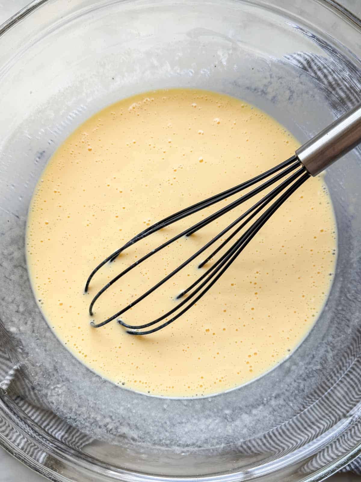 Eggs, milk, sour cream, salt, and pepper whisked in a large mixing bowl.
