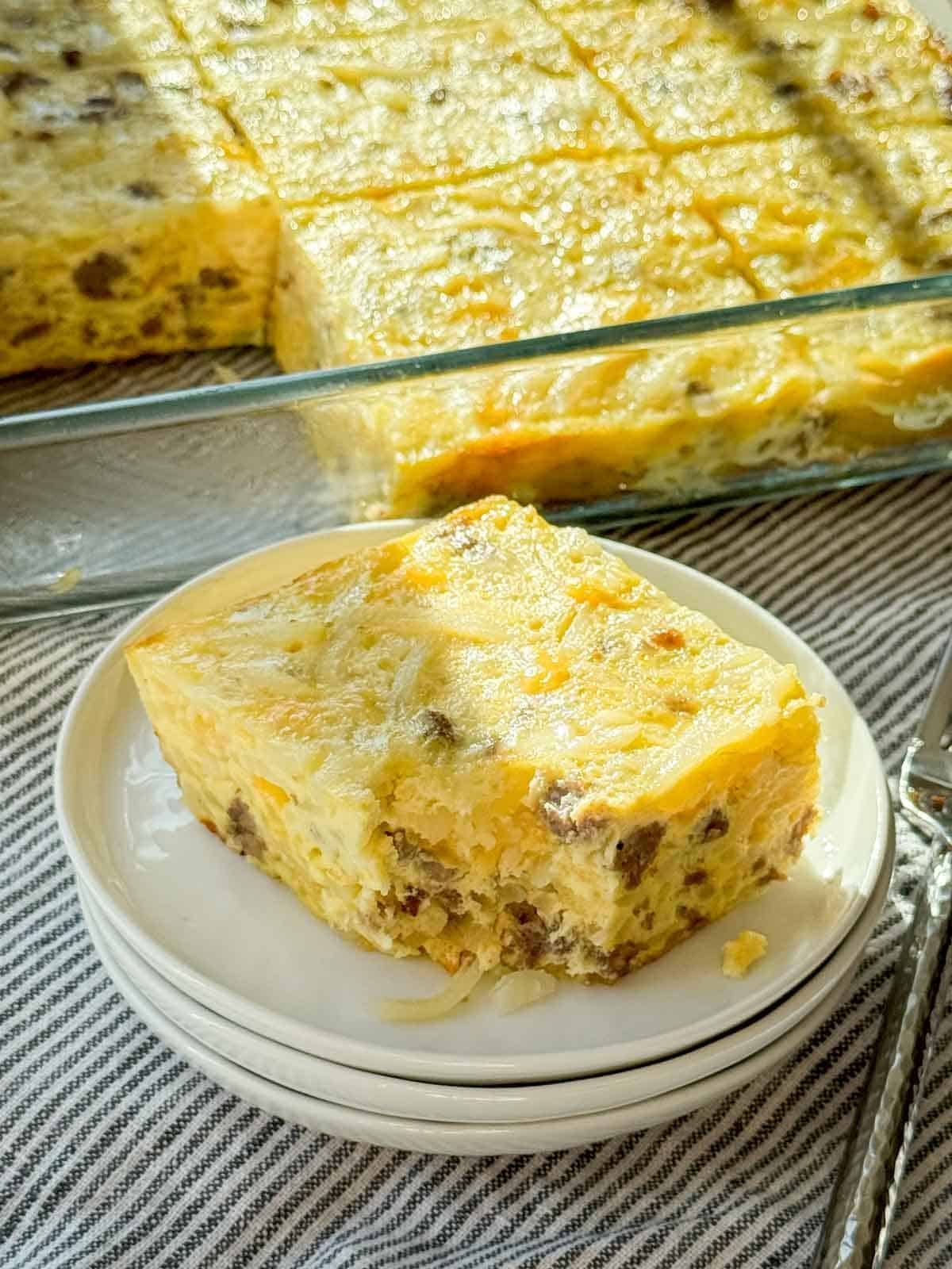 A generous slice of cheesy sausage and hash brown breakfast casserole on a plate.